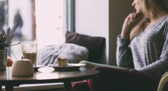 Woman sat in coffee shop with cake